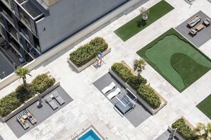An aerial view of a hotel with a swimming pool, sun loungers, and a well-maintained garden. - City Views / Pool & Gym / Near Circle Mall JVC (Dubai)