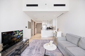 A modern living room with a flat-screen TV, a grey sofa, and a coffee table. - City Views / Pool & Gym / Near Circle Mall JVC (Dubai)