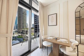 A modern hotel room with a dining area, large windows, and a view of the cityscape. - Central Business Bay / Balcony / Pool & Gym (Dubai)