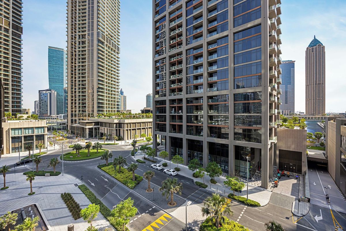 A modern urban area with high-rise buildings, a roundabout, and a well-maintained green space.