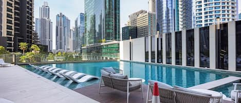 Un espace piscine aménagé sur le toit, avec des chaises longues et une vue sur le panorama urbain.