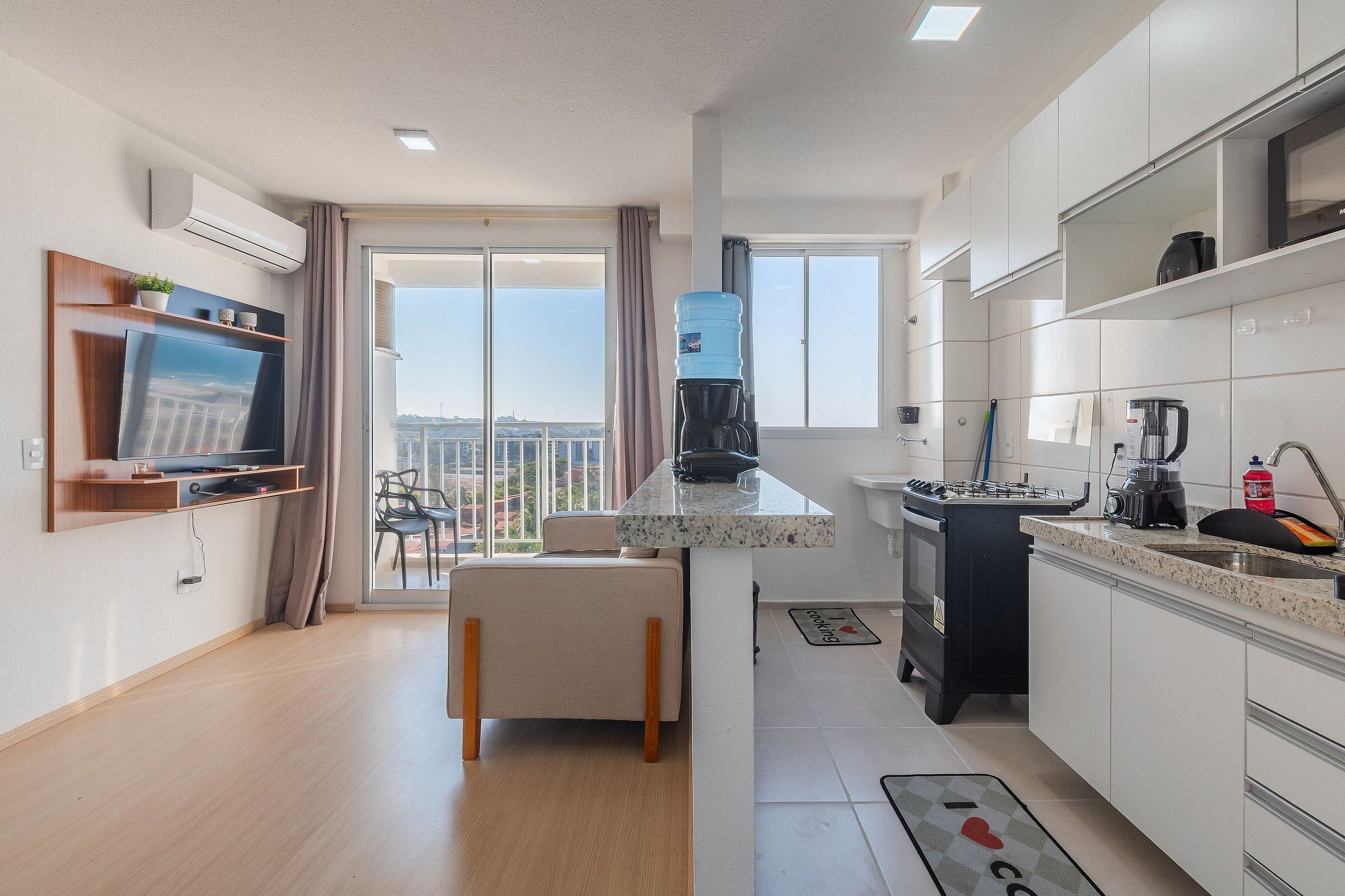 A modern kitchen with a built-in stove, a water dispenser, and a large window offering a city view.