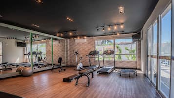 A gym with exercise equipment, large windows, and a mirror.