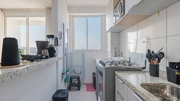 Een kleine keuken met een gasfornuis, een koffiezetapparaat en een spoelbak.