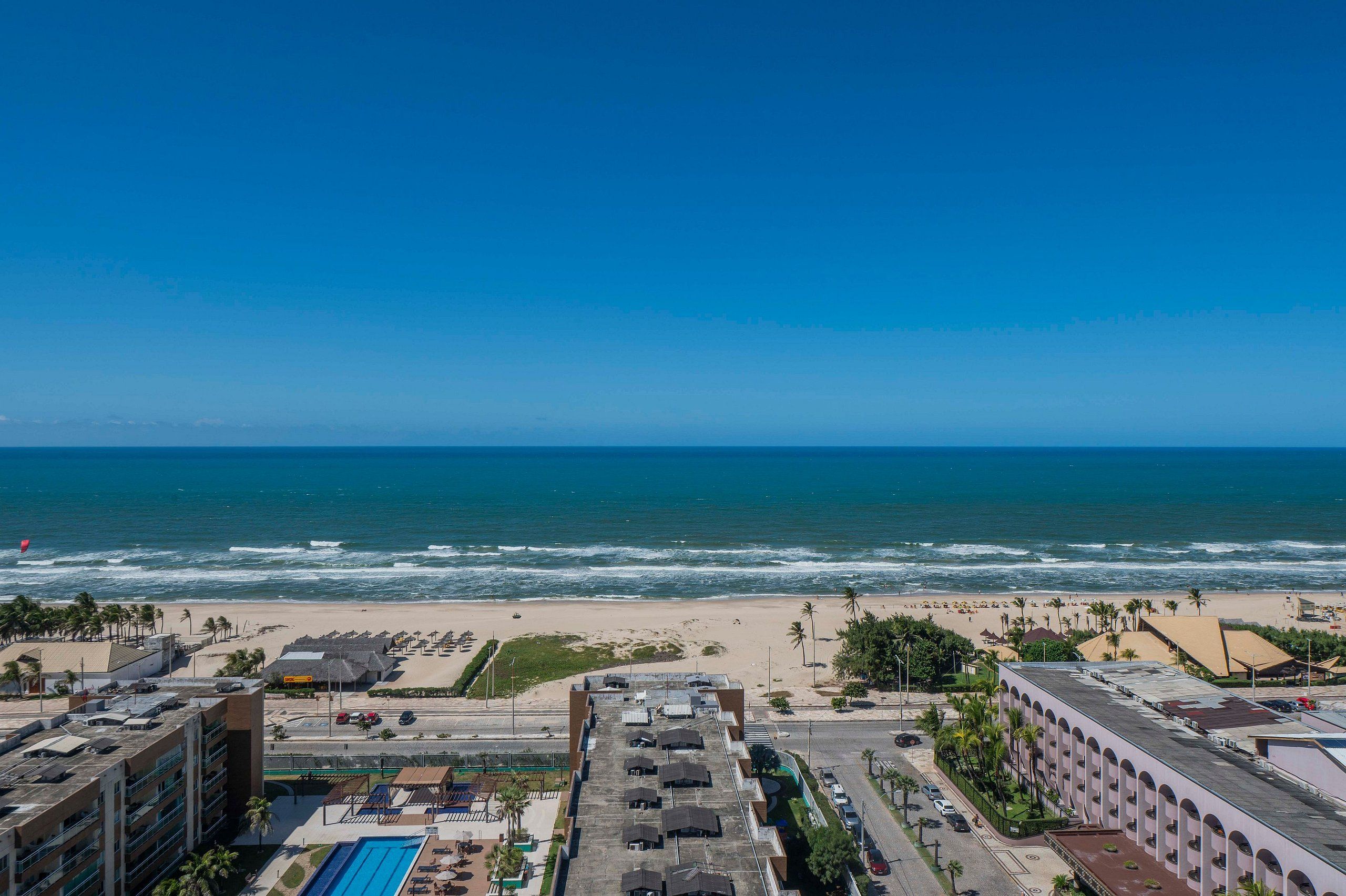 A coastal cityscape with a beach, buildings, and a clear sky.