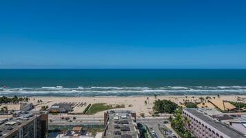 A coastal cityscape with a beach, buildings, and a clear sky.