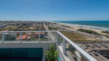 A rooftop terrace with a view of a coastal cityscape, including a beach and ocean.