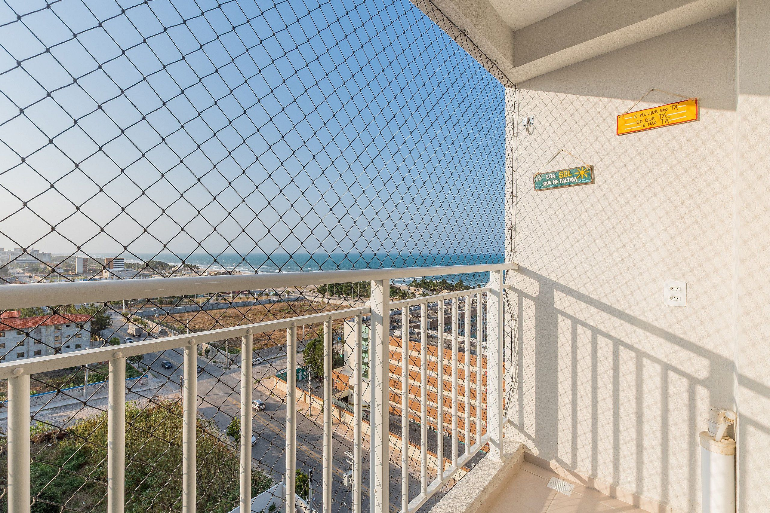 A balcony with a chain-link fence overlooking a coastal area.