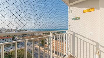 A balcony with a chain-link fence overlooking a coastal area.