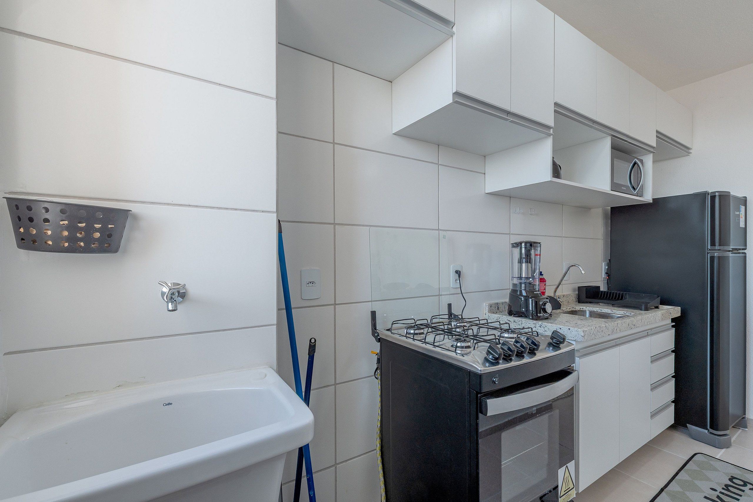 Una cocina moderna con gabinetes blancos, estufa a gas, refrigerador y pileta.