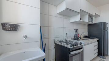 Una cocina moderna con gabinetes blancos, estufa a gas, refrigerador y pileta.