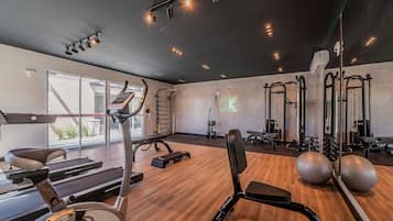 Un gimnasio con equipo cardiovascular, pesas libres y un espejo de pared.