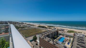 A high-rise hotel with a rooftop pool, a beach view, and a parking area.