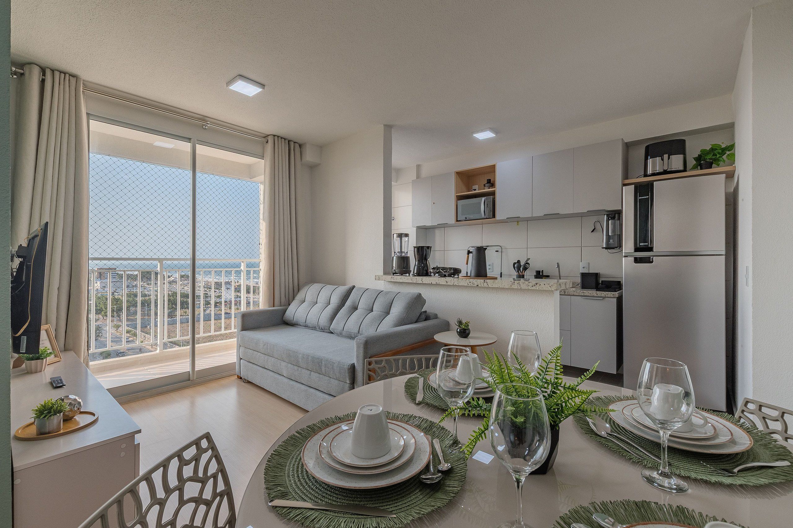 A modern apartment with a balcony, a dining area set for a meal, and a kitchen with contemporary appliances.