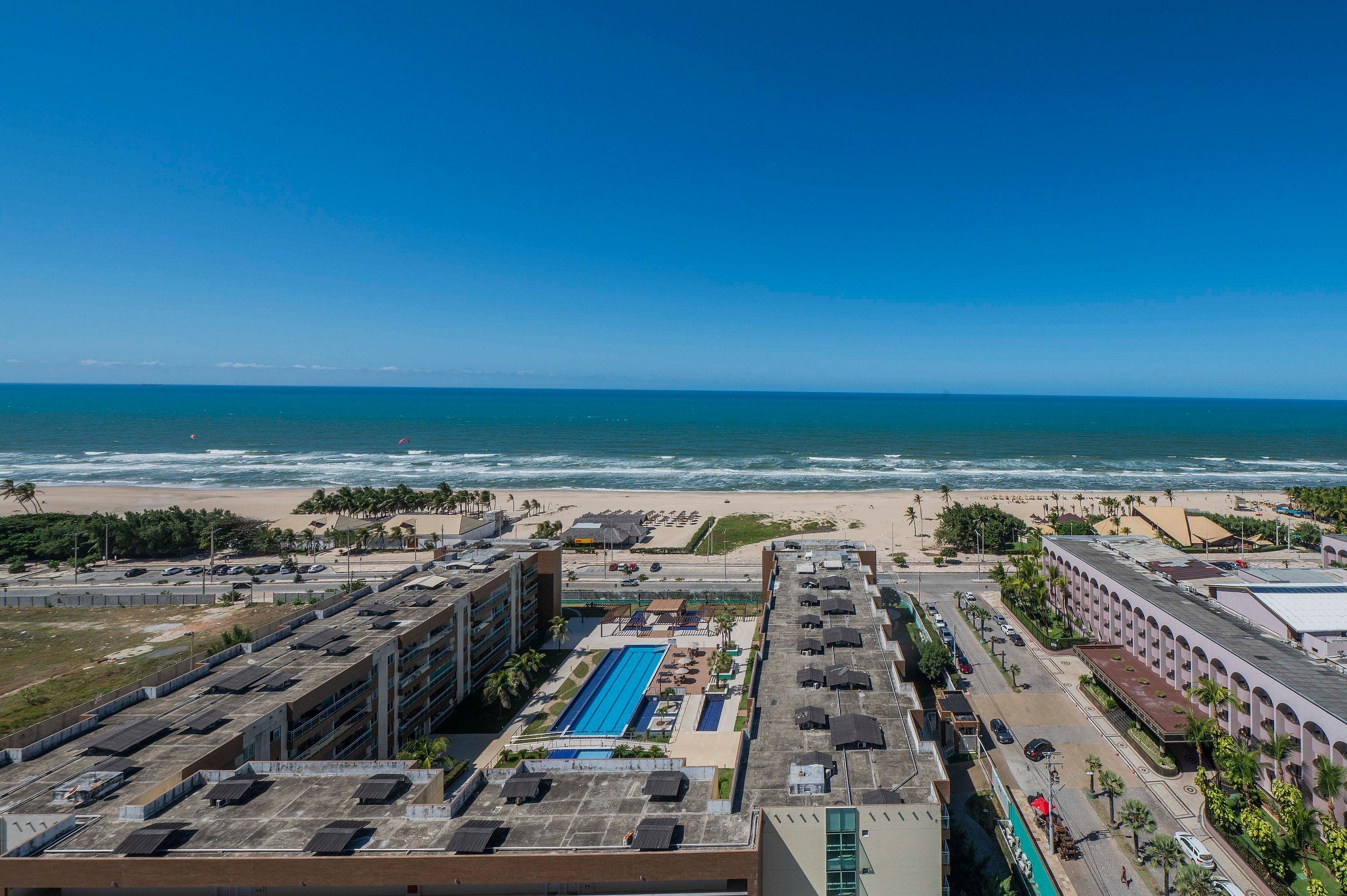 Een kusthotel met een zwembad op het dak, toegang tot het strand en uitzicht op de oceaan.
