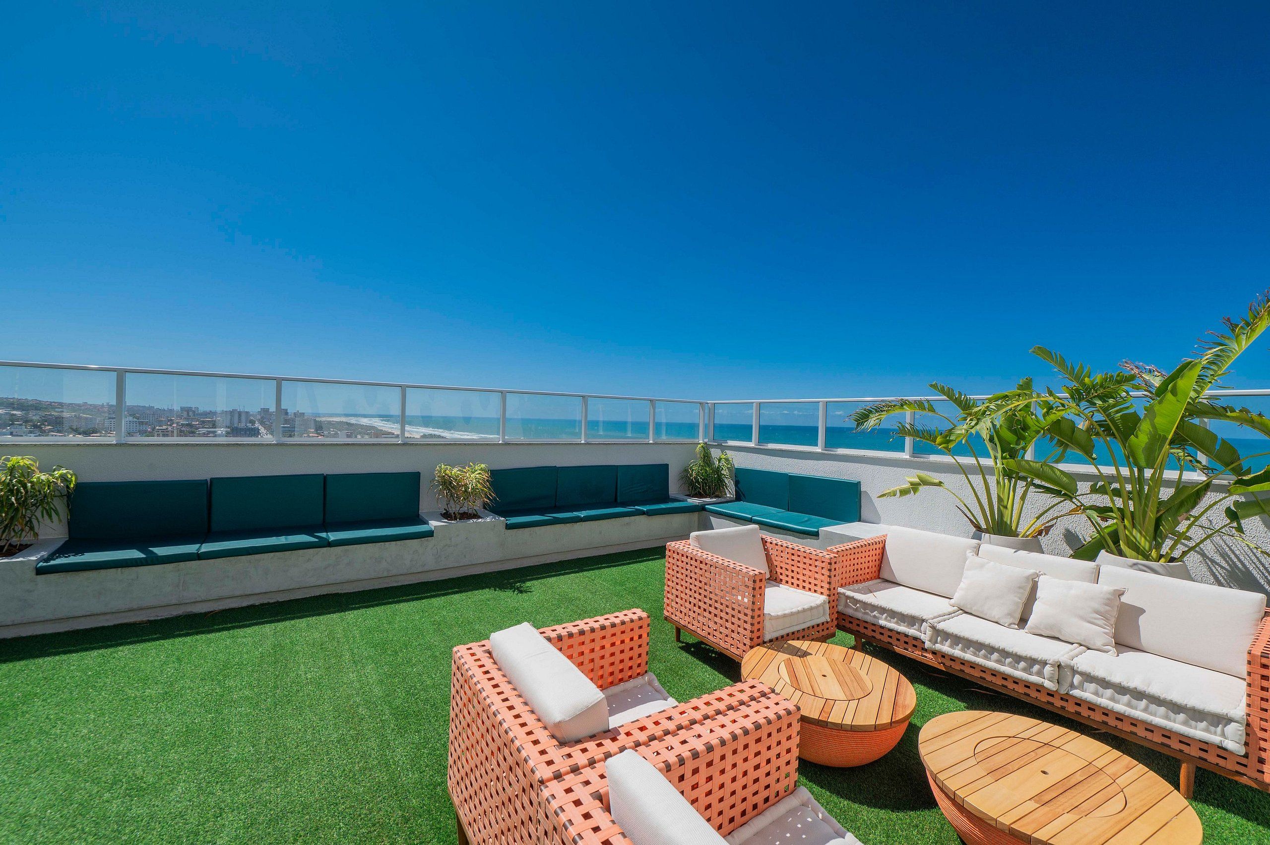 Una terraza en la azotea con mobiliario exterior, vistas de la ciudad y una piscina al fondo.