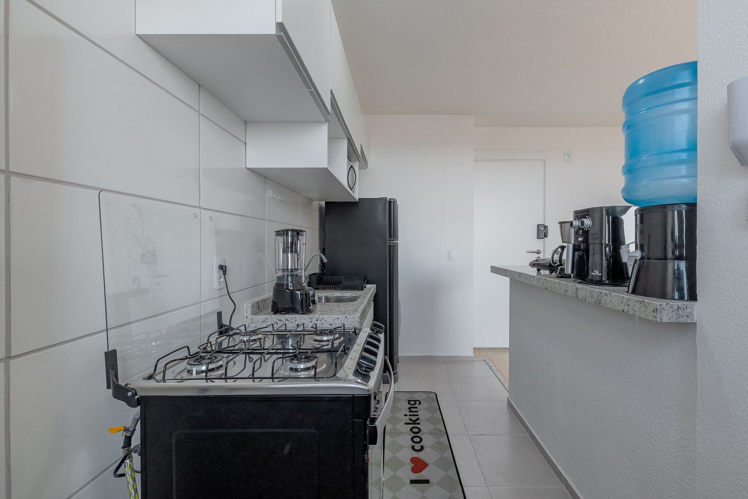 A modern kitchen with a gas stove, a coffee machine, and a water dispenser.