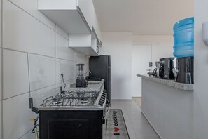 A modern kitchen with a gas stove, a coffee machine, and a water dispenser. - Vista Mar Condominium Club 300 Meters From Praia do Futuro by Carpediem (Fortaleza)