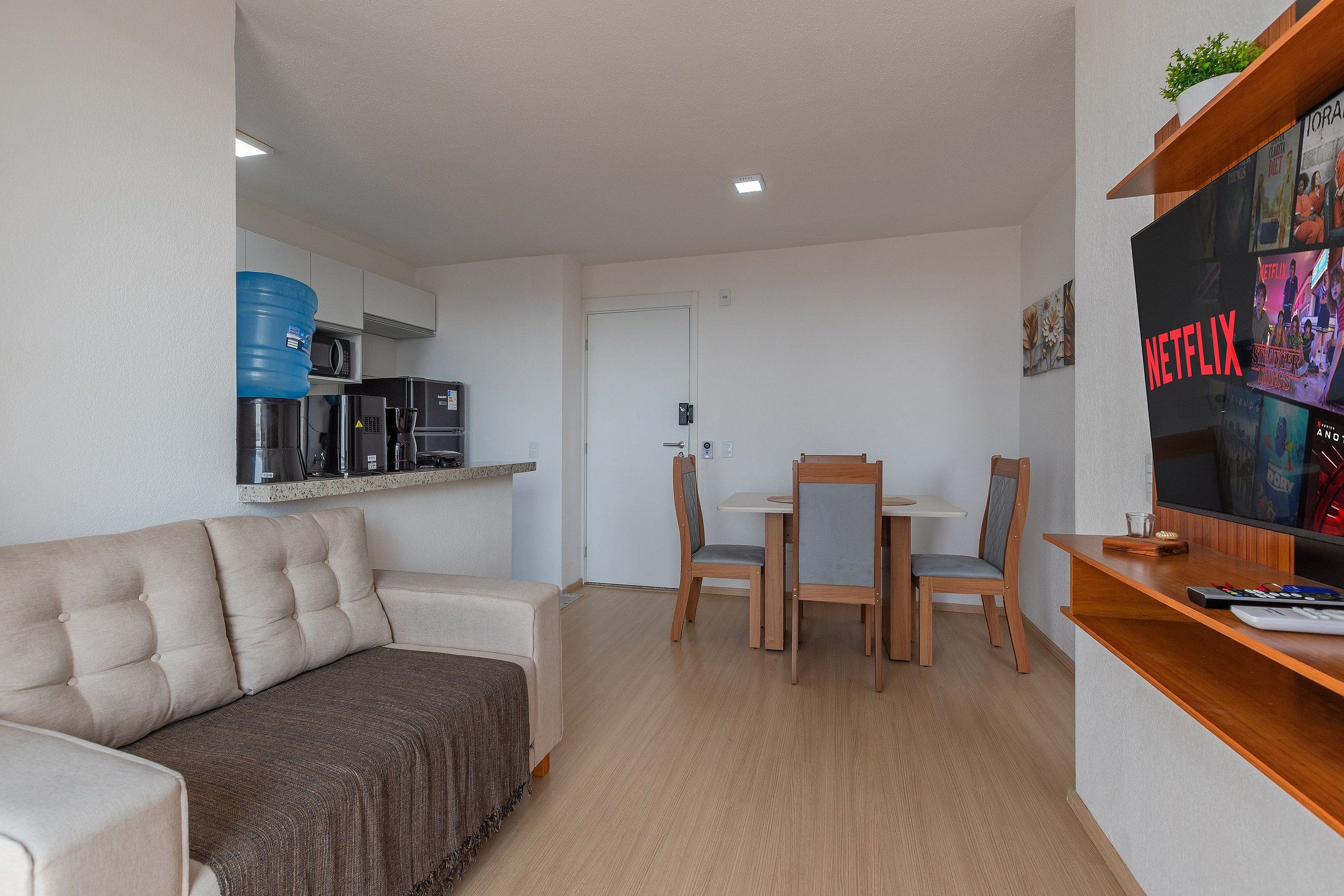 Un espacio habitable compacto con kitchenette, comedor y zona de estar con televisor.