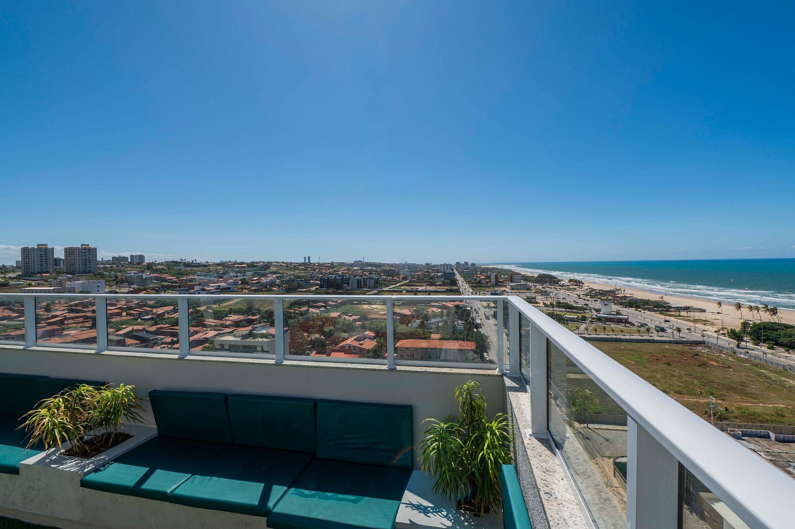 A balcony with a view of a coastal cityscape, including a beach and high-rise buildings.