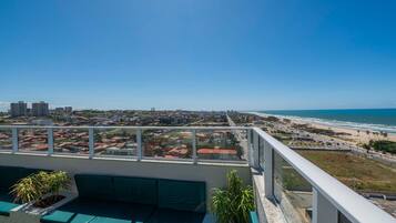 A balcony with a view of a coastal cityscape, including a beach and high-rise buildings.