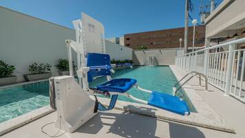 Zona junto a la piscina con un puesto de salvavidas, una silla de reposo azul y vista despejada al agua.