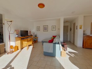 A spacious living area with a sofa, television, and a wooden cabinet. - Peaceful apartment in nature - 4 guests (Morbier)