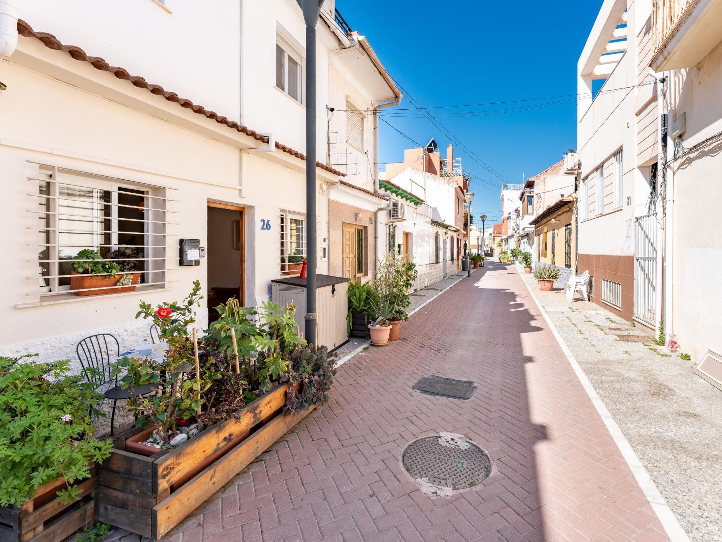 Eine schmale Straße gesäumt von Gebäuden, manche mit Balkonen und Blumenkästen.