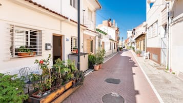Eine schmale Straße gesäumt von Gebäuden, manche mit Balkonen und Blumenkästen.