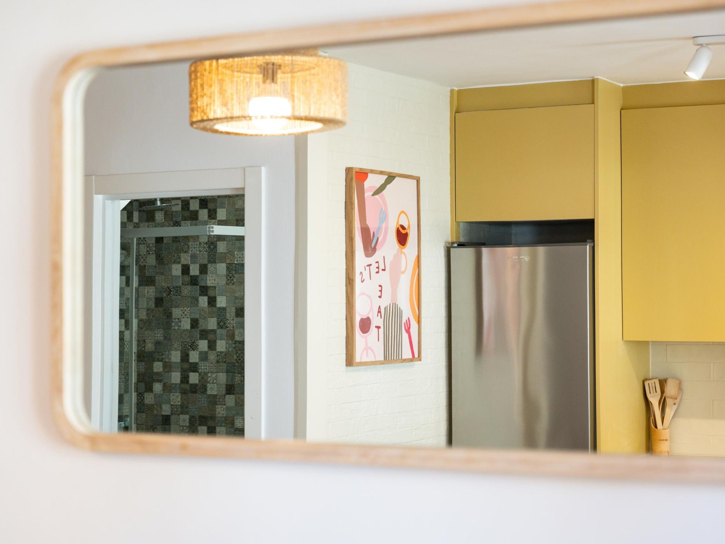A kitchen with a stainless steel refrigerator, a hanging light fixture, and a tiled backsplash.