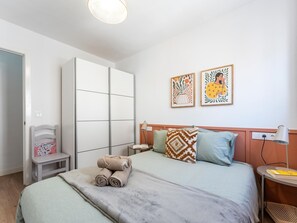 A bedroom with a bed, a nightstand, a chair, a wardrobe, and two wall art pieces. - Traditional house in Pedregalejo - 4 guests (Málaga)