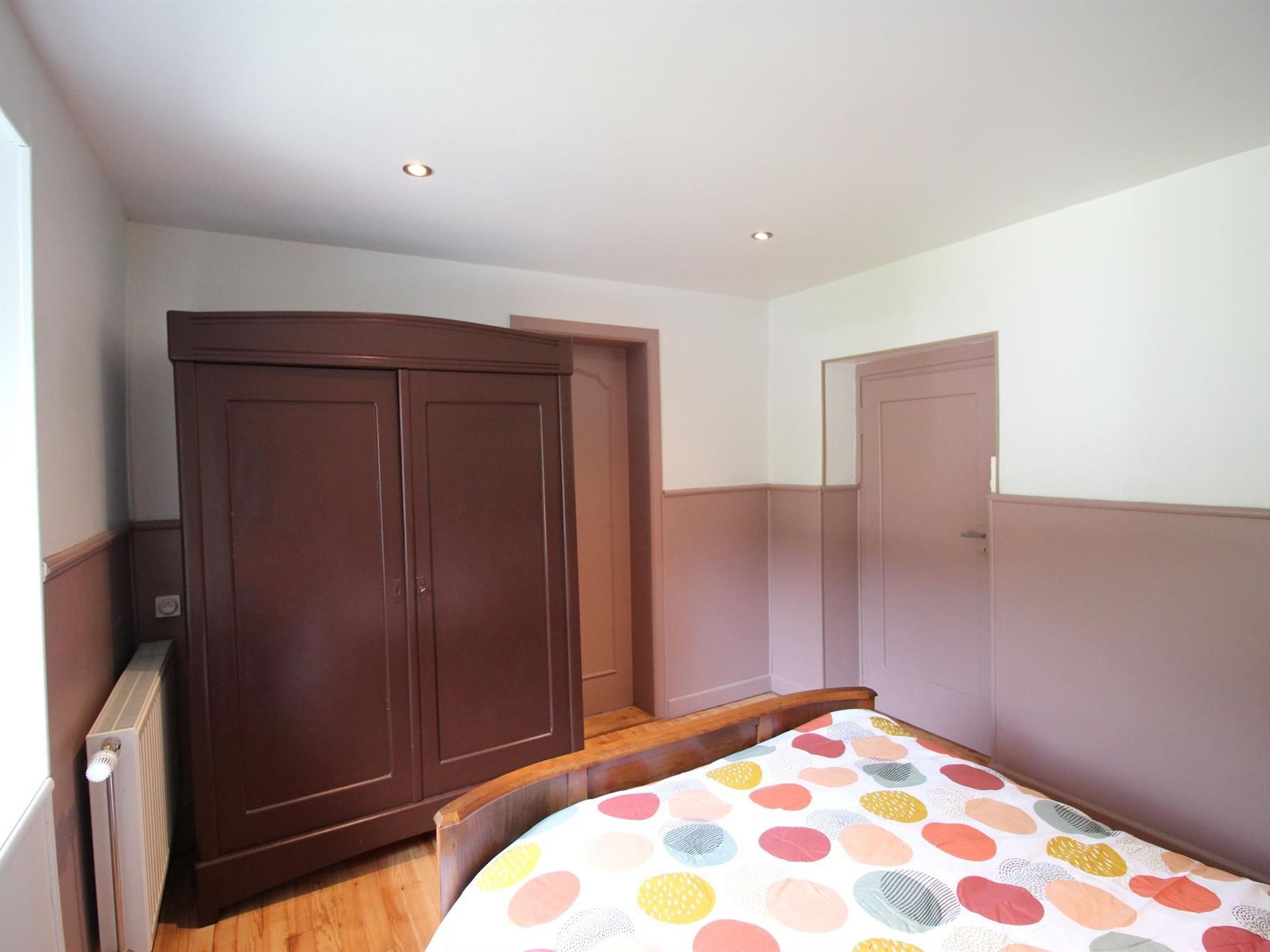 Un dormitorio con una cama, un armario y una puerta.