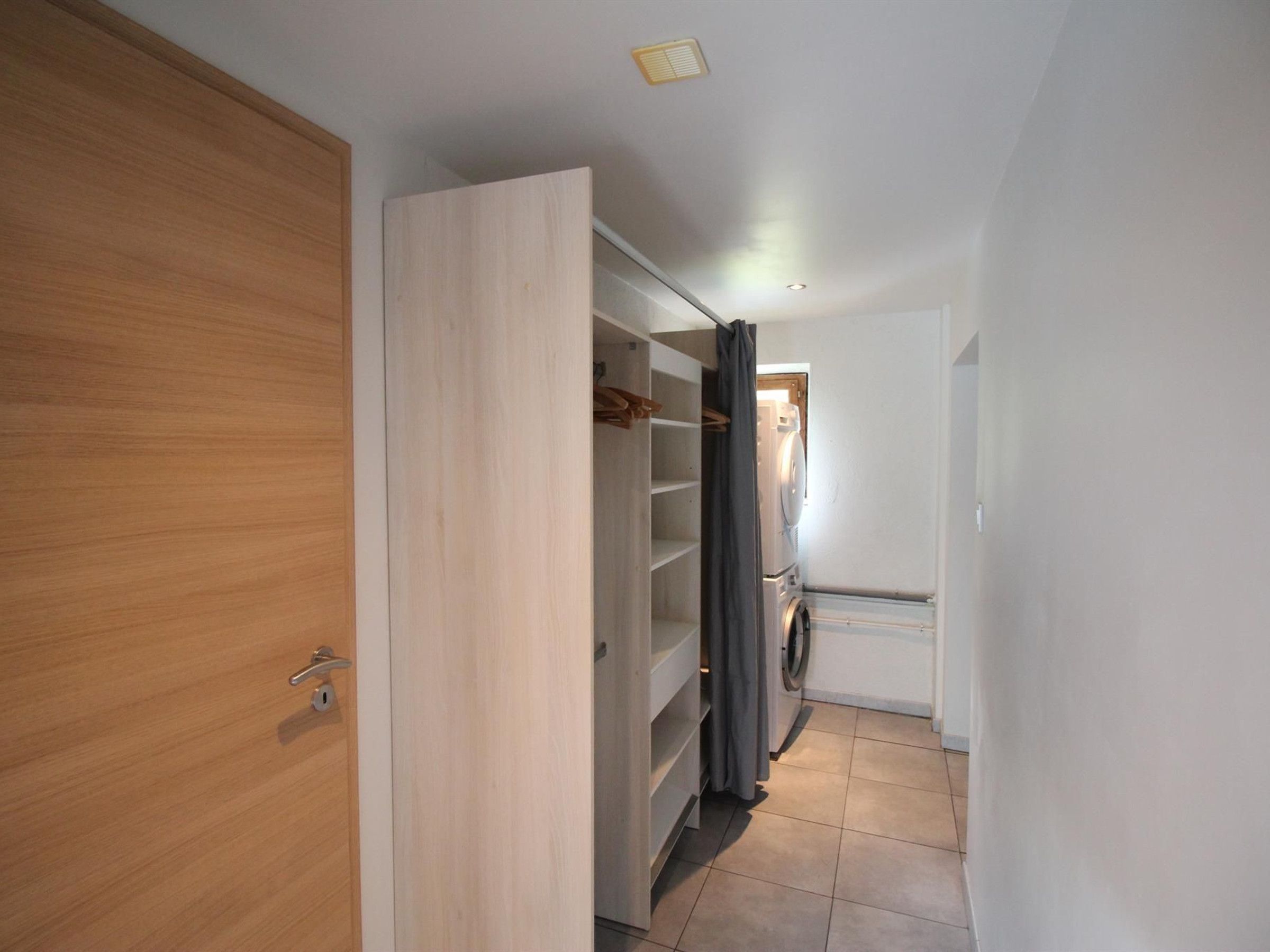 Ein Flur mit einem Holzschrank, einem Einbauschrank und einer Waschmaschine.
