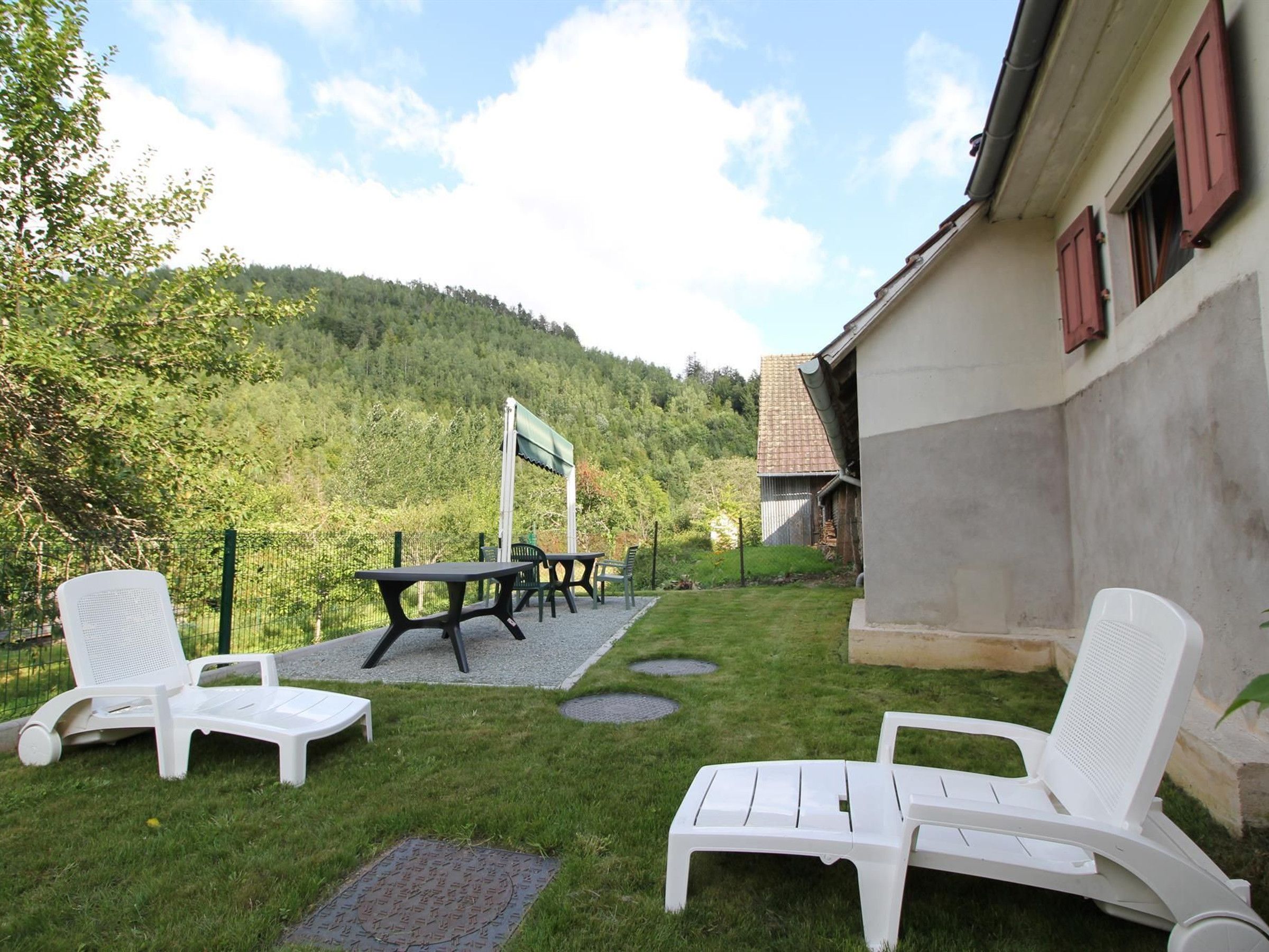 En terrasse med udendørs møbler, et bord og udsigt til en skovklædt bakke.