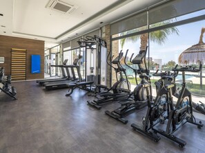 A gym with various exercise equipment, large windows, and a view of a pool and palm trees. - Contemporary residence, pets welcome - 6 guests (Marbella)