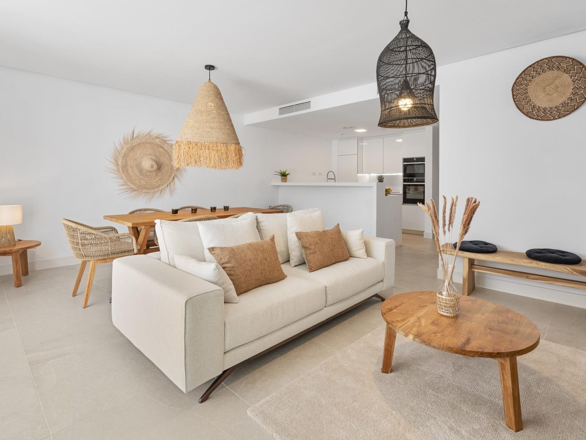 A modern living room with a sofa, round wooden coffee table, and hanging rattan light fixtures.