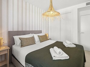 A neatly made bed with white and patterned pillows, a green throw blanket, and two rolled towels on the bed. - Contemporary residence, pets welcome - 6 guests (Marbella)
