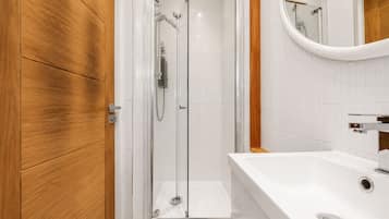 Ein modernes Badezimmer mit einer gläsernen Dusche, einem Holzbadezimmer-Möbel und einem weißen Waschbecken.