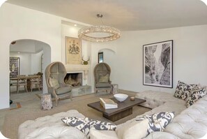 Ein Wohnzimmer mit Kamin, bequemen Sitzgelegenheiten und Kunstwerken an den Wänden.