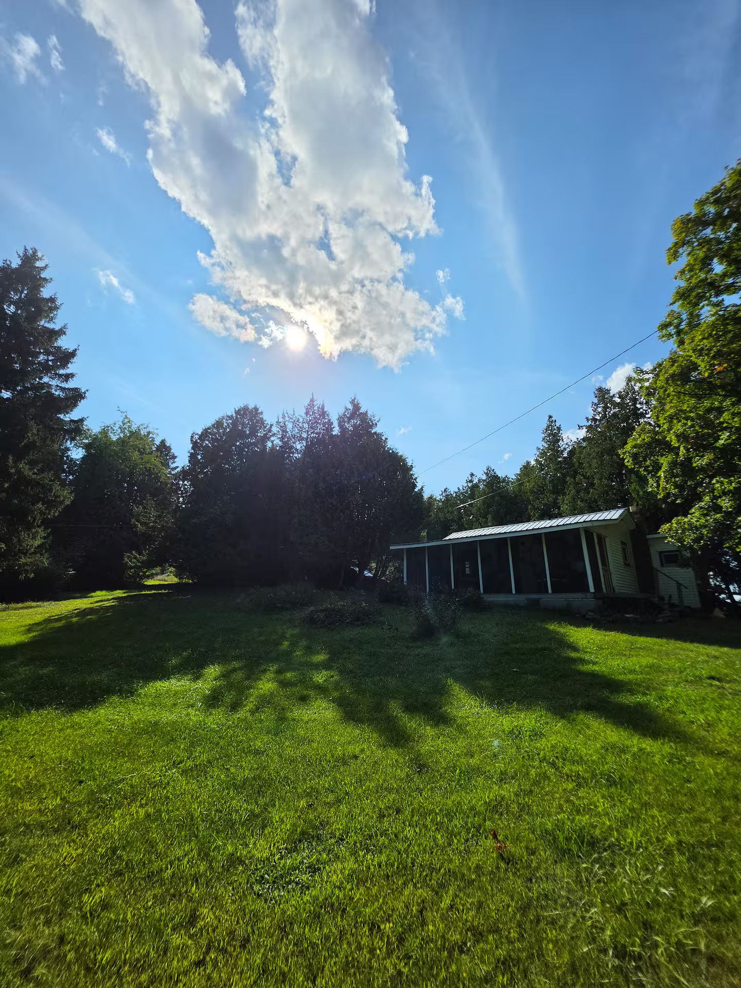 A grassy outdoor area with a building that has a sloped roof and a porch.