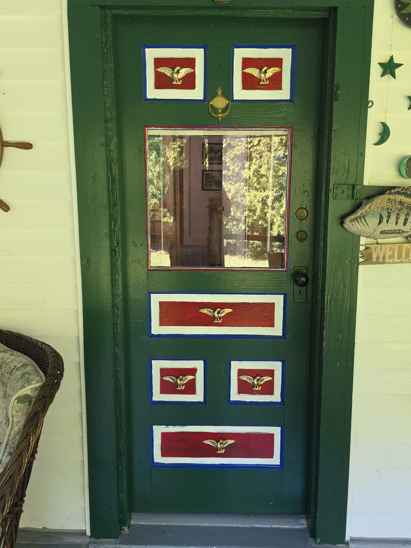 A green door with a window, decorated with eagle emblems and a welcome sign.