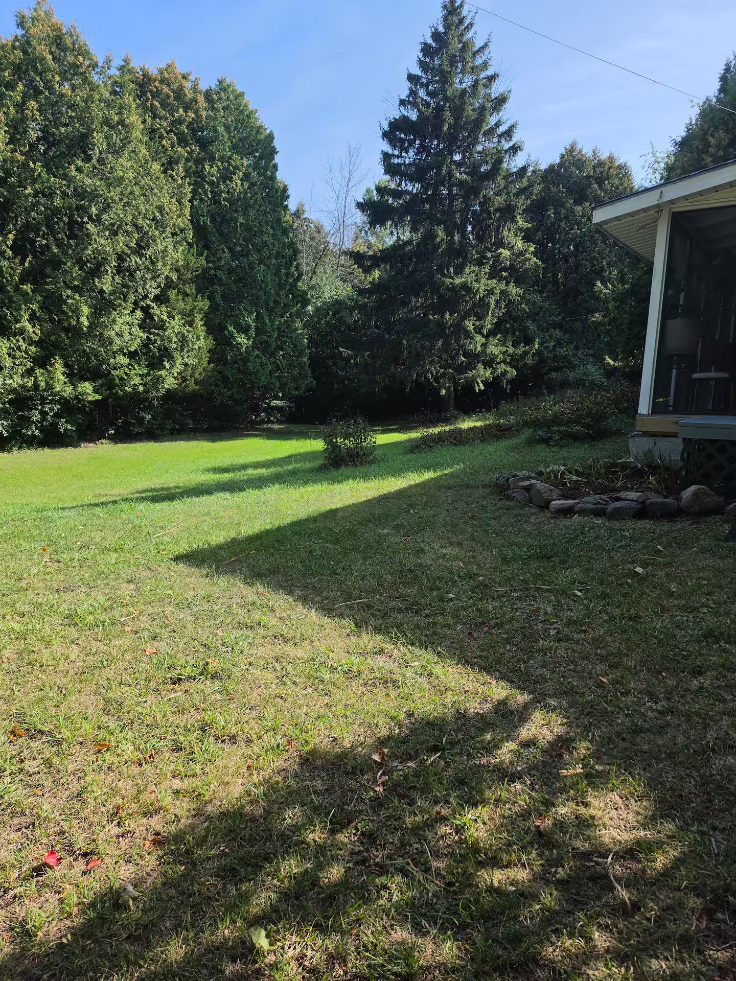 A residential property with a well-maintained lawn, a small garden area, and a house with a porch.