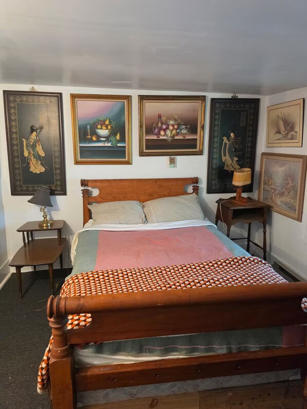 Un dormitorio con una cama de madera, una mesita de noche, una lámpara y cuadros en la pared.