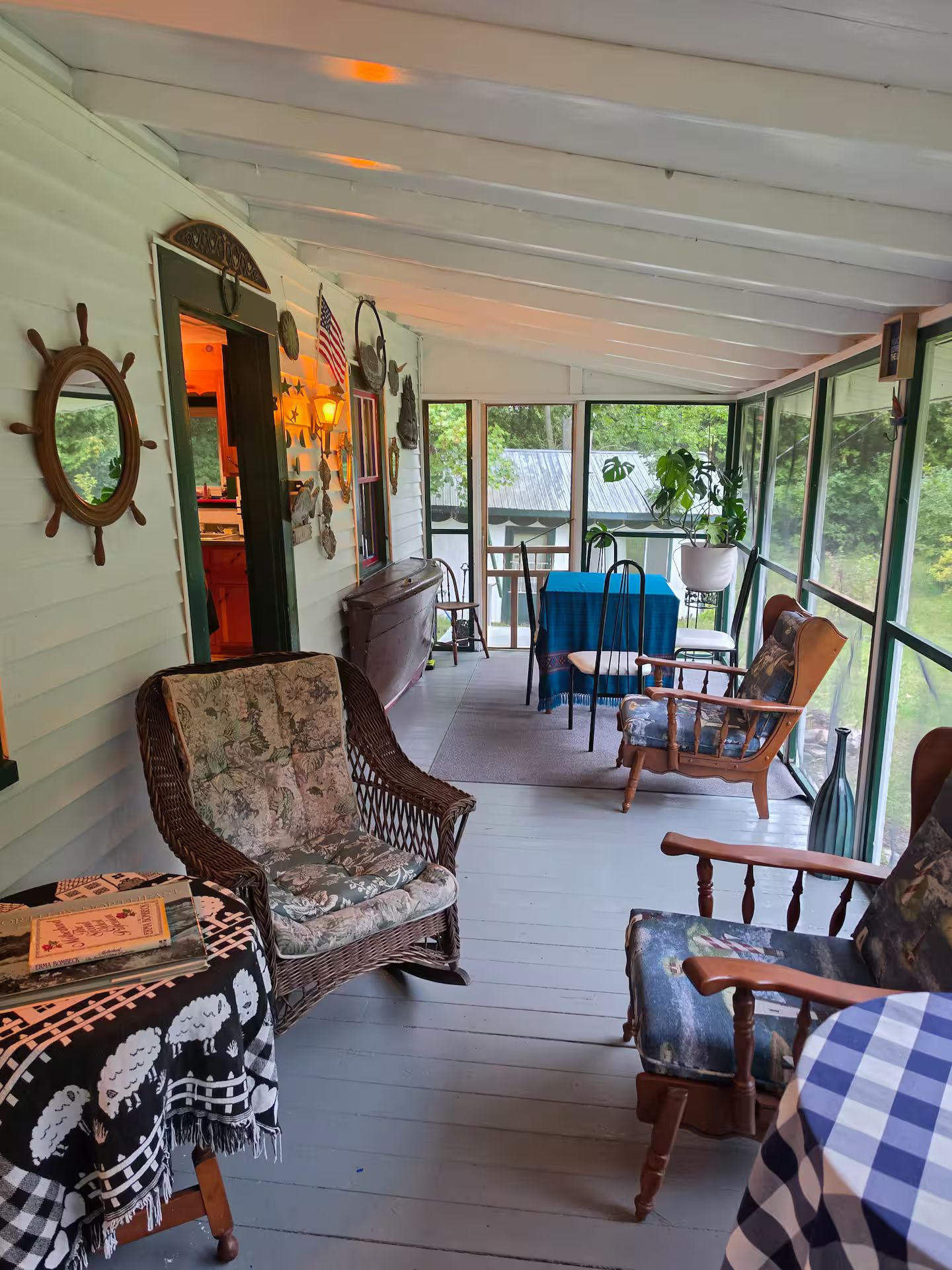 Een overdekt terras met rieten meubels, een tafel met een blauwe tafelkleed en decoratieve objecten aan de muren.