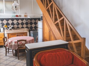 A kitchen with a dining table, chairs, a refrigerator, and a wooden staircase. - Charming quiet cottage - 2 guests (Choloy-Ménillot)