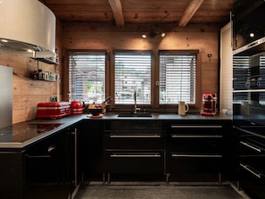 A modern kitchen with a wooden ceiling, a built-in oven, and a sink. - Cozy apartment in village center - 8 guests (La Clusaz)