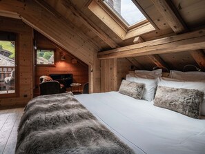 A cozy wooden cabin with a loft bedroom featuring a large bed, a fireplace, and a skylight. - Cozy apartment in village center - 8 guests (La Clusaz)