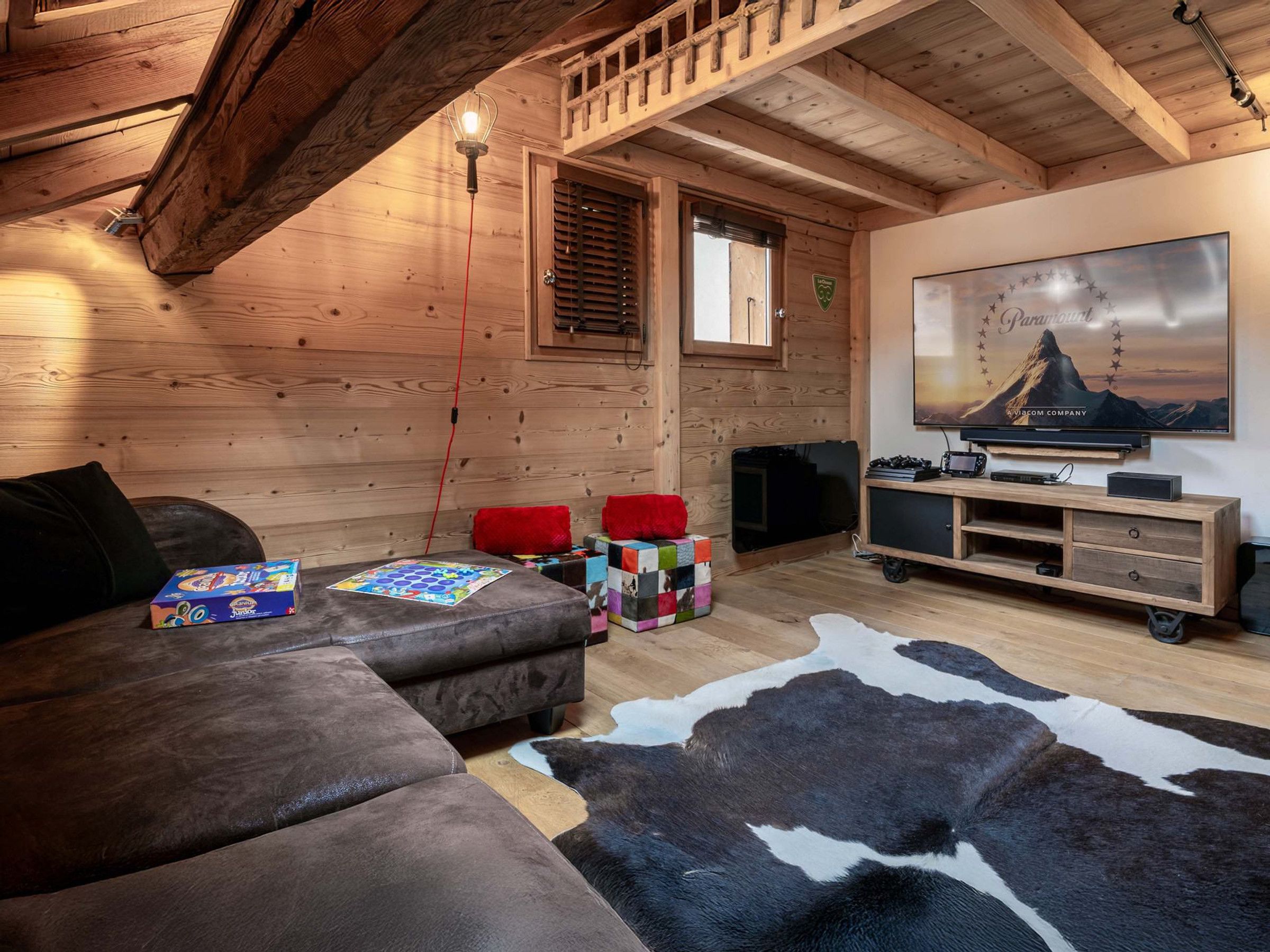 A cozy room with a wooden ceiling, a sofa, a television, and a mounted picture.