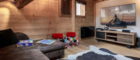 Una habitación acogedora con techo de madera, un sofá, un televisor y un cuadro colgado.