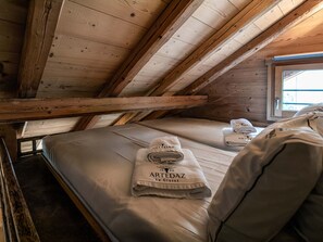 A small, cozy attic bedroom with wooden beams, a bunk bed, and a window providing natural light. - Cozy apartment in village center - 8 guests (La Clusaz)